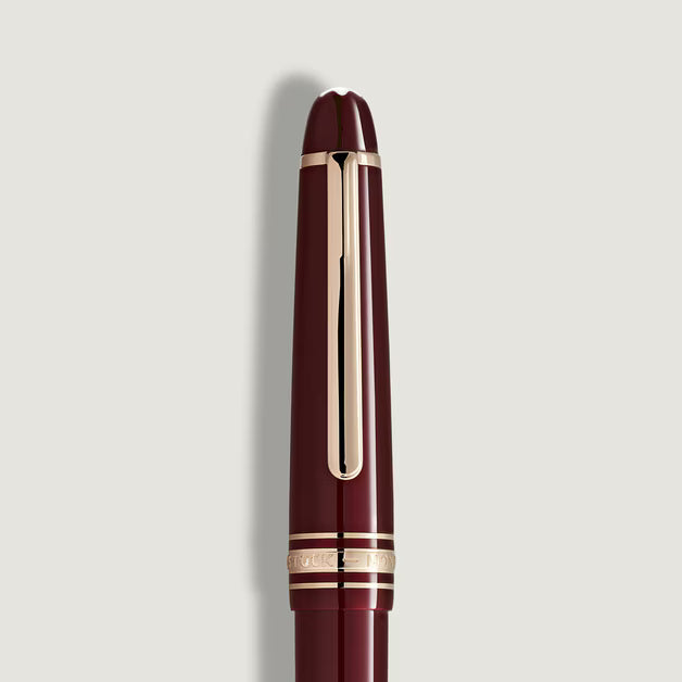 Maroon pen with gold accents on a light gray background