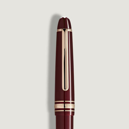 Maroon pen with gold accents on a light gray background
